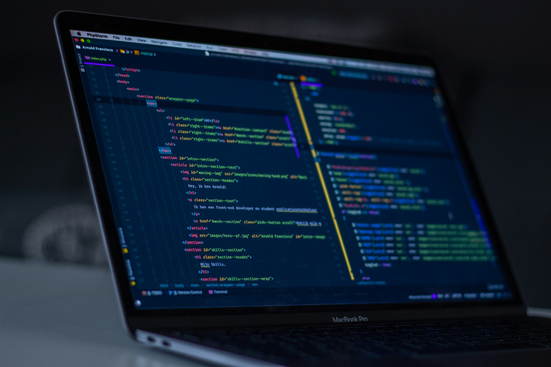 Developer writing code on a laptop screen showing colorful syntax-highlighted programming