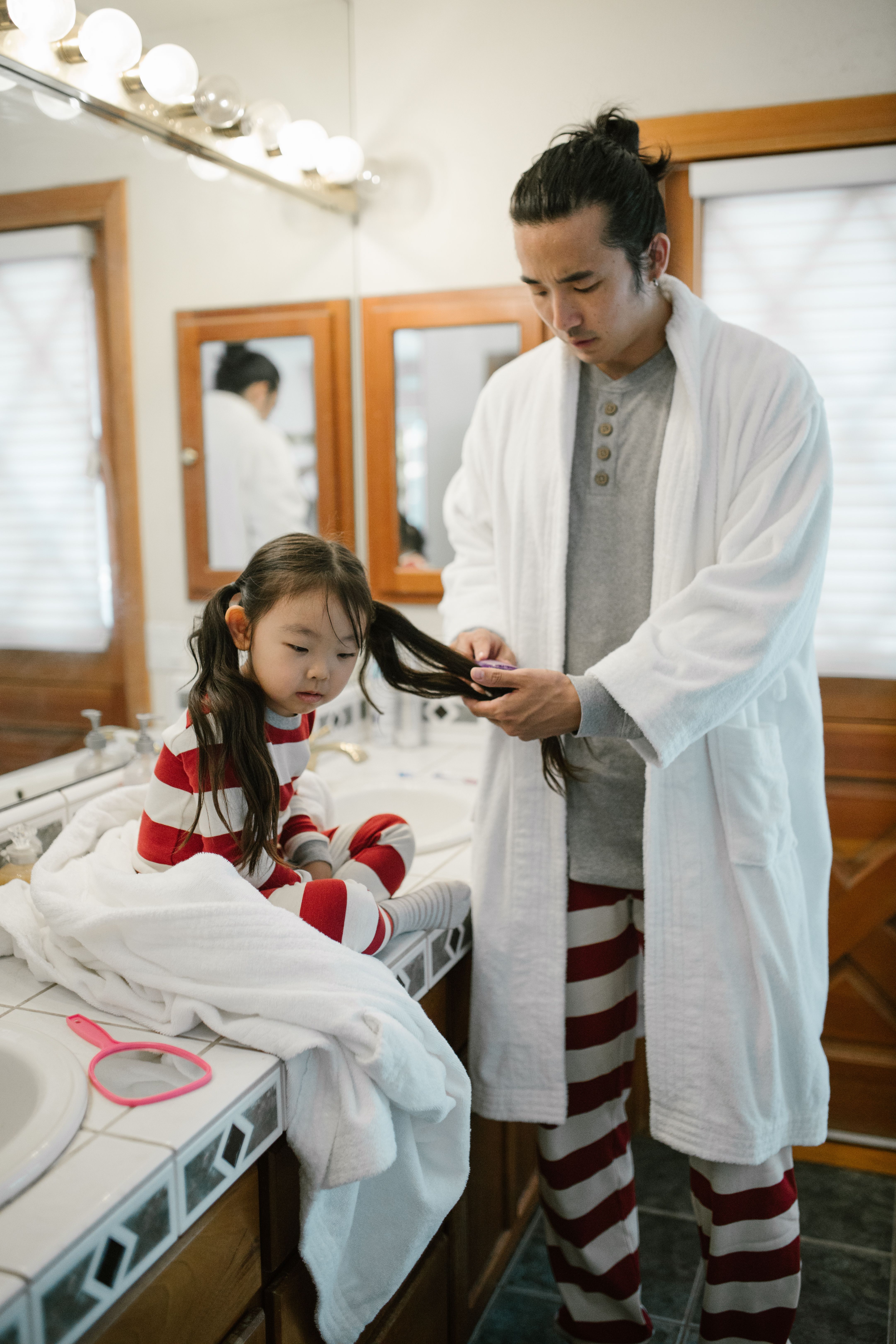 Father combing his daughter's hair, an intimate act of care that transcends words