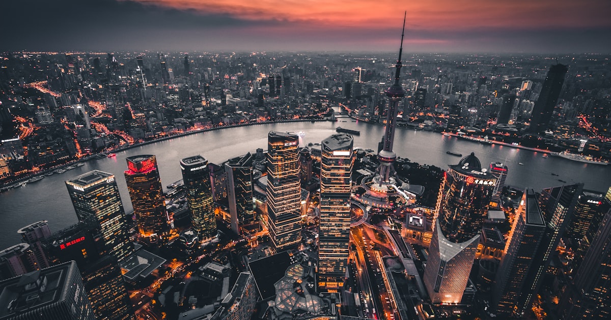 A wide aerial view of Shanghai's Pudong skyline and residential towers at dusk, representing the city's long-term housing market outlook