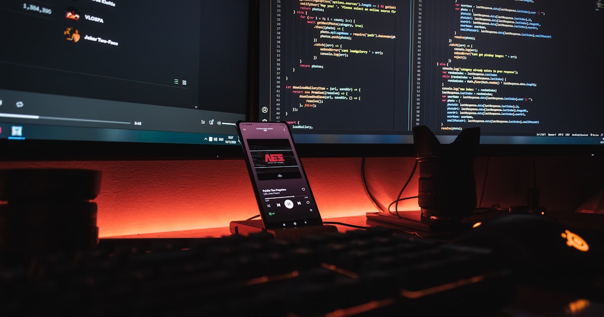 A person working at a computer in a dark office lit by screen glow